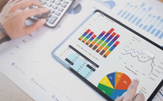 Person analyzing data on tablet with charts and using calculator